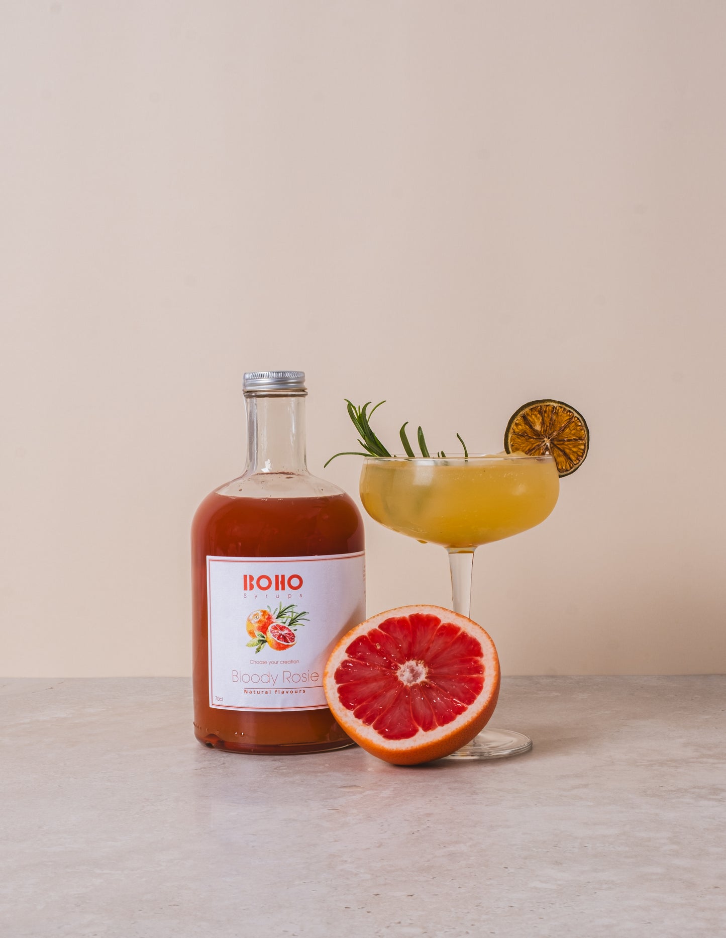 Fles BOHO bloedappelsien rozemarijn siroop met een glas ernaast – frisse en kruidige combinatie