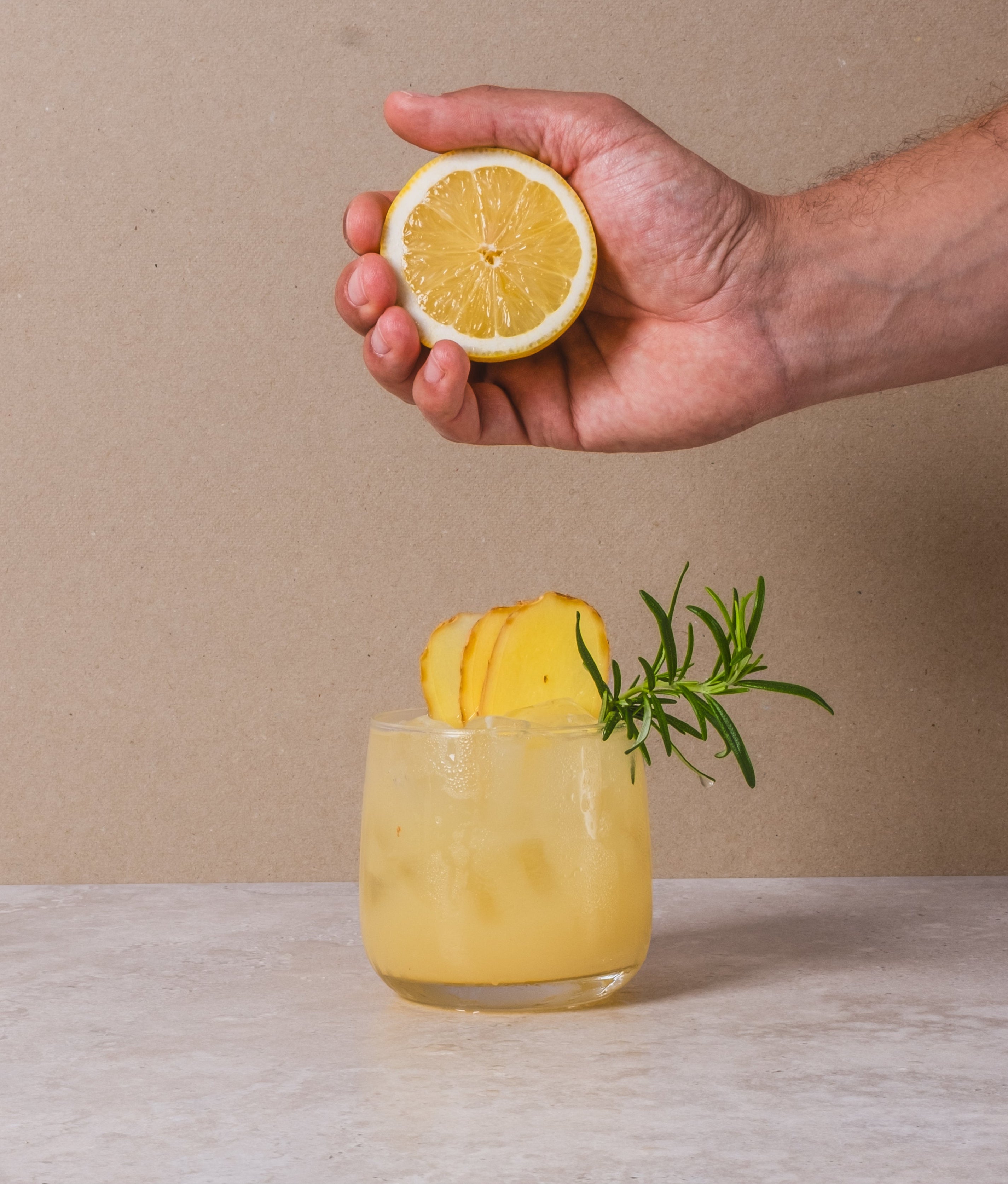 Glas gember citroen limonade waarin een verse halve citroen wordt uitgeknepen – verfrissend homemade drankje met BOHO siroop