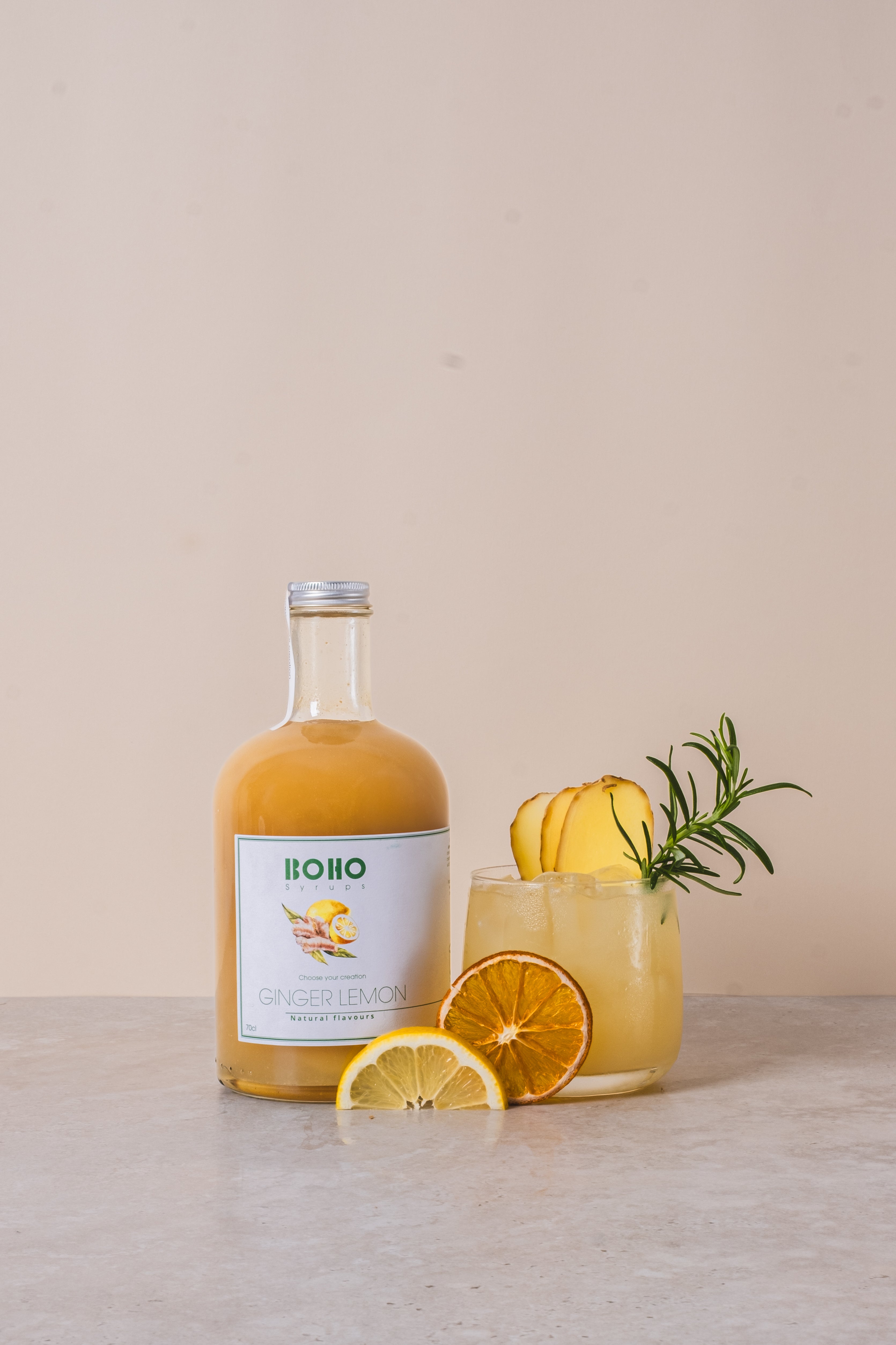 Fles BOHO gember citroen siroop met een homemade gember citroen limonade ernaast – frisse en pittige dorstlesser
