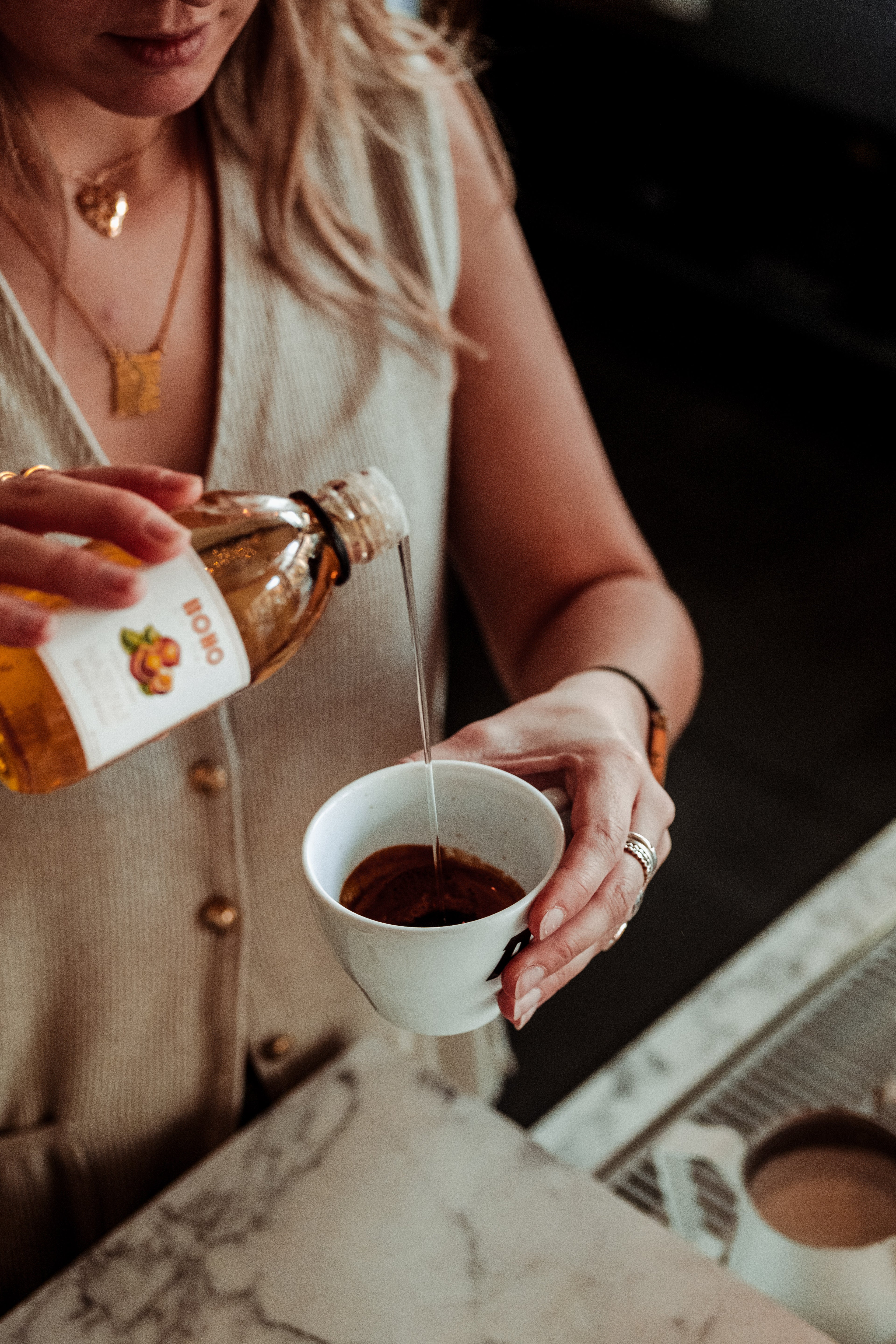 Barvrouw giet BOHO hazelnoot siroop bij een Americano, gefotografeerd in zij- en bovenaanzicht – nootachtige toets voor een volle koffiesmaak