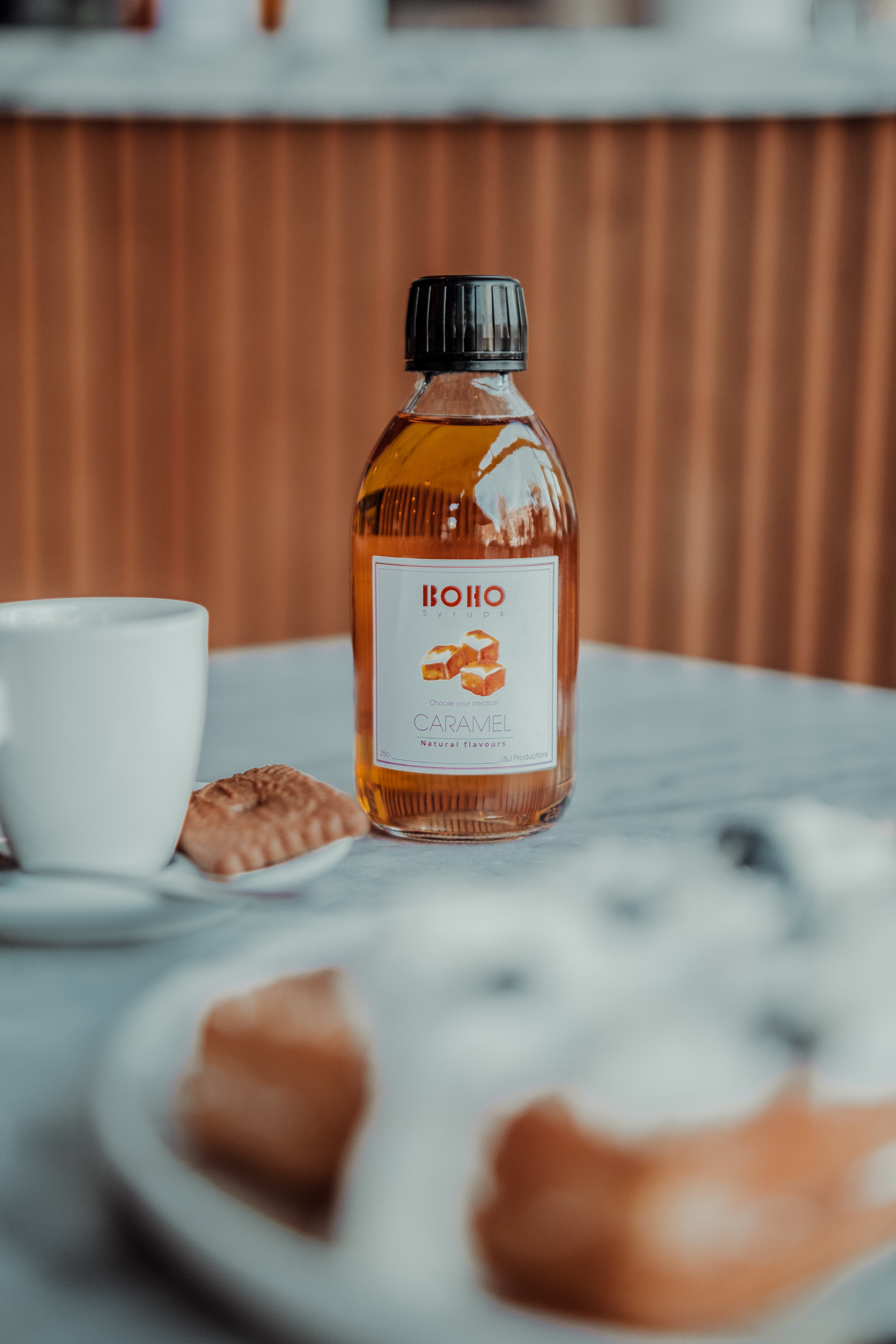 Flesje BOHO karamel siroop op een tafeltje in de koffiebar – zoete toevoeging voor koffie en desserts