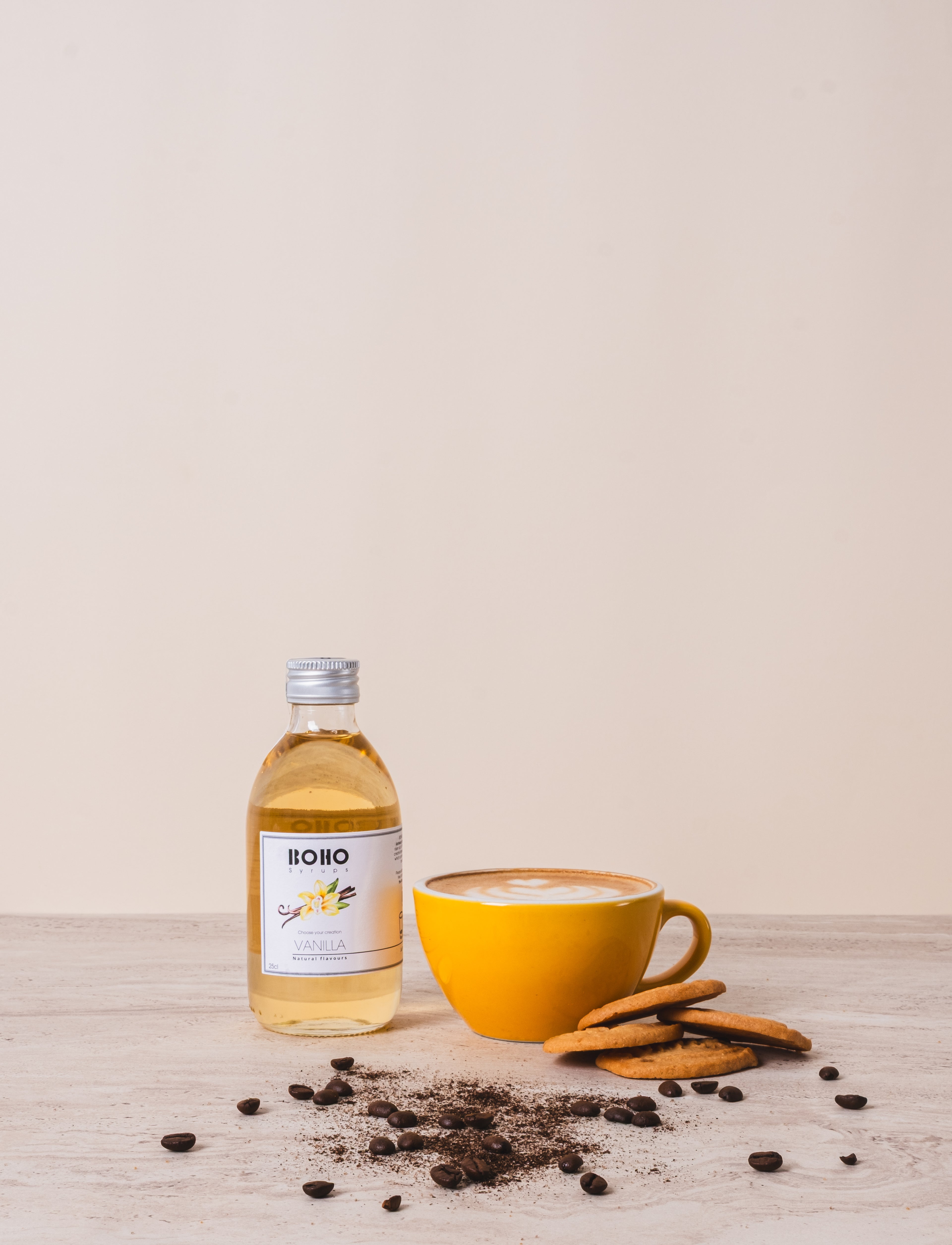 Flesje BOHO vanille siroop naast een cappuccino – zachte en romige koffiesmaak met vanilletoets