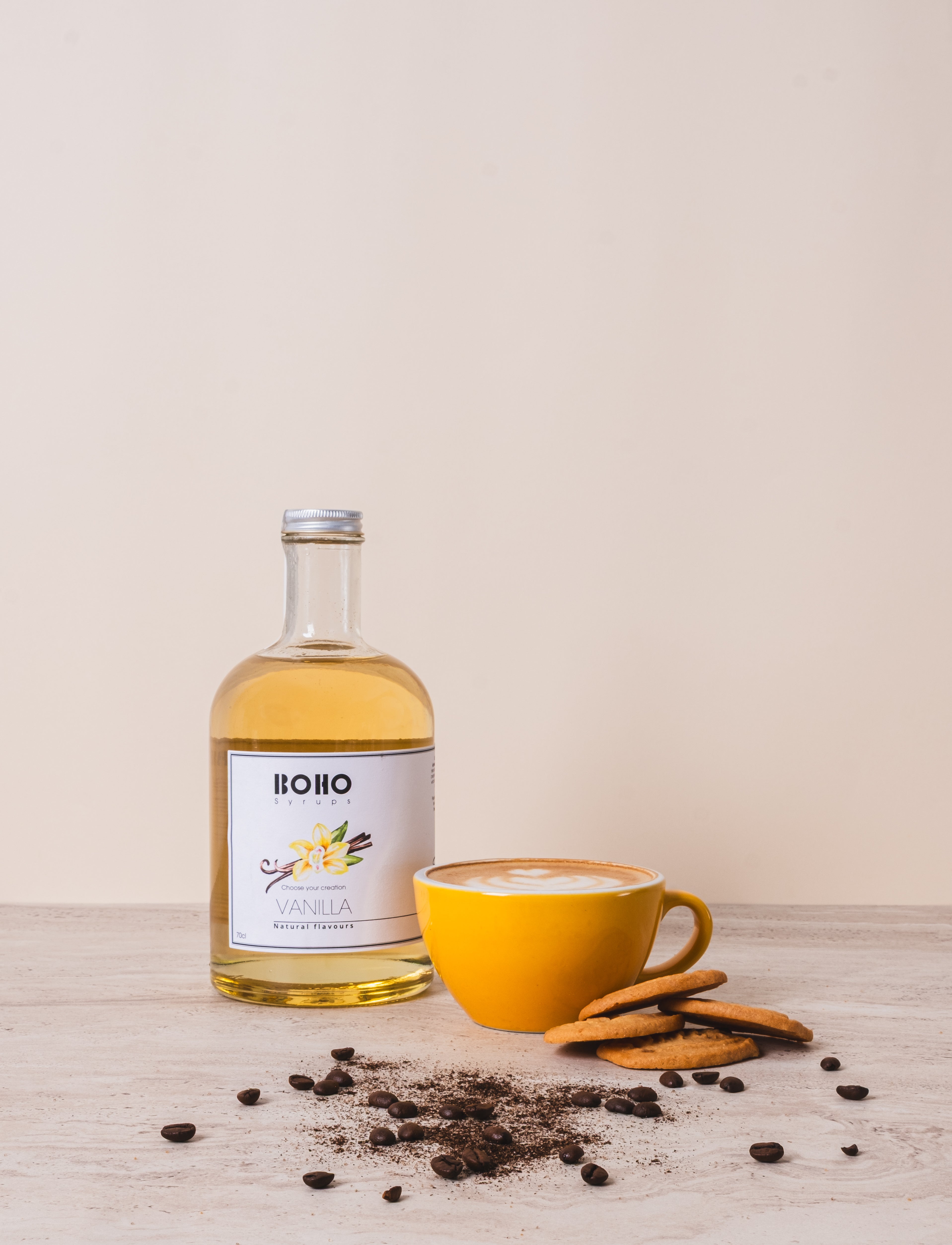 Grote fles BOHO vanille siroop met een cappuccino ernaast – romige koffie met een zachte vanilletoets