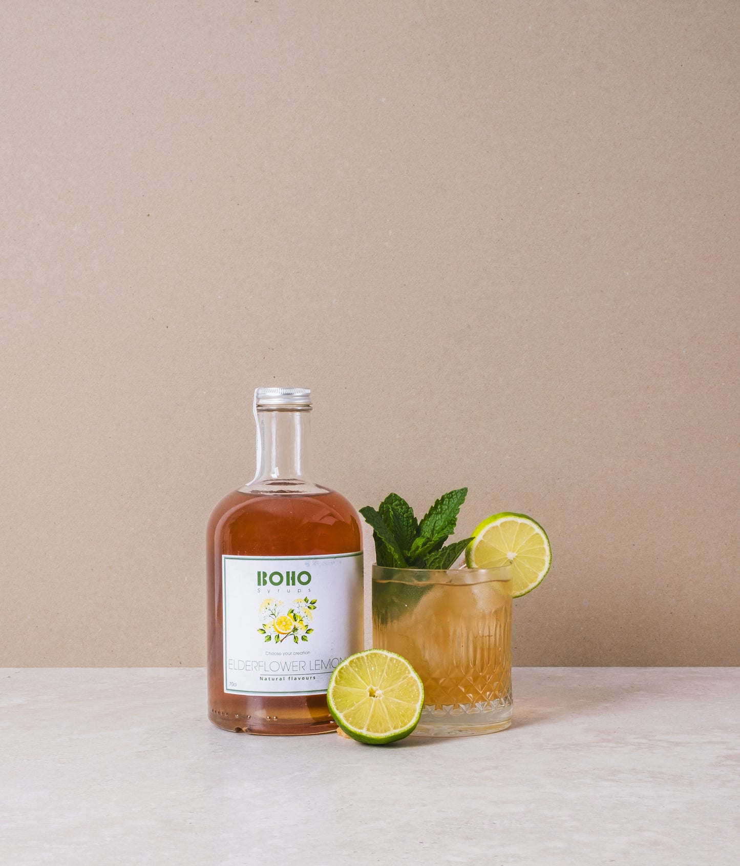 Fles BOHO vlierbloesem citroen siroop met daarnaast een mooi gegarneerde limonade – bloemig en verfrissend drankje