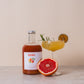Fles BOHO bloedappelsien rozemarijn siroop met een glas ernaast – frisse en kruidige combinatie