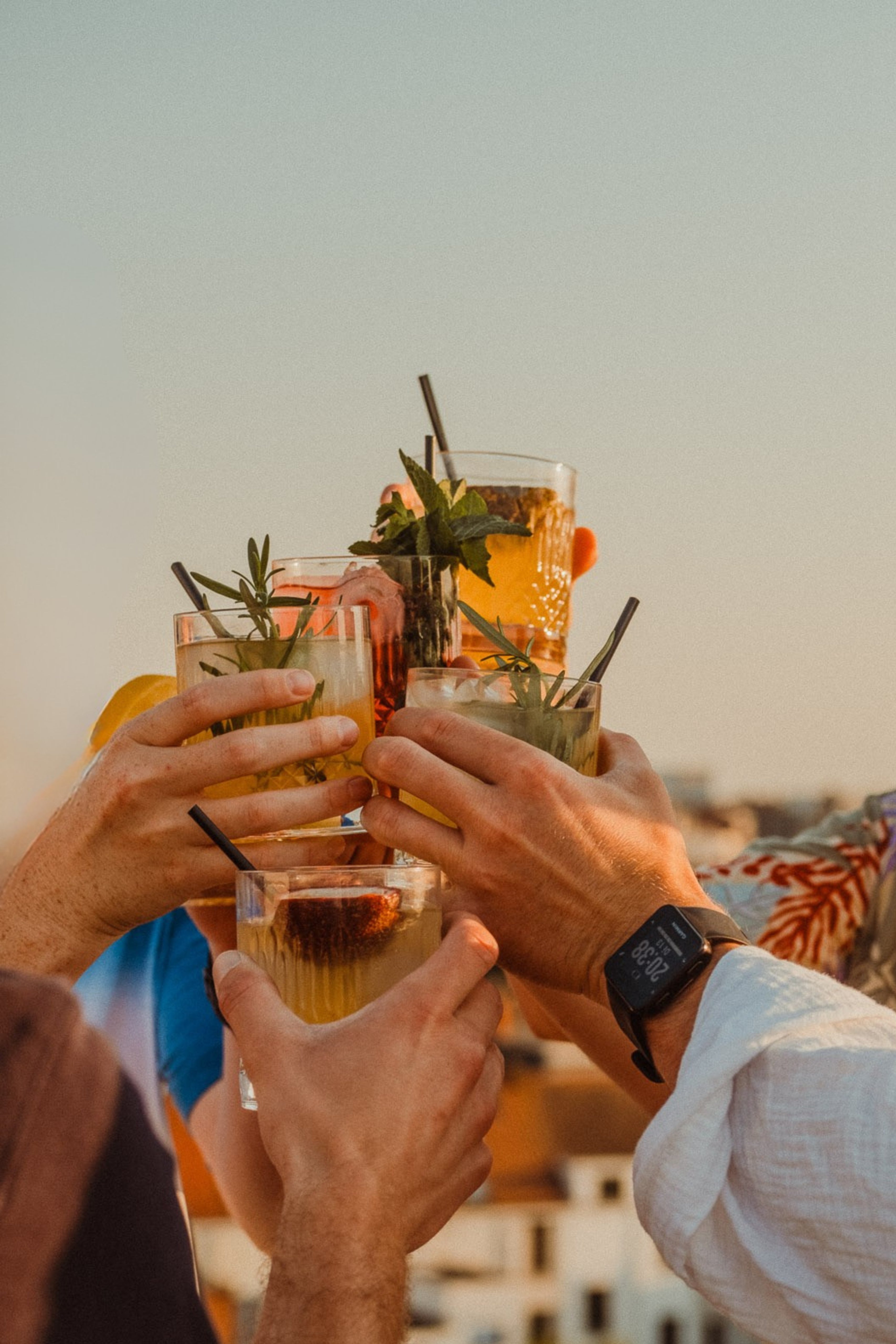 Groep vrienden die glazen homemade mocktails laten klinken in de zon, gemaakt met BOHO Syrups