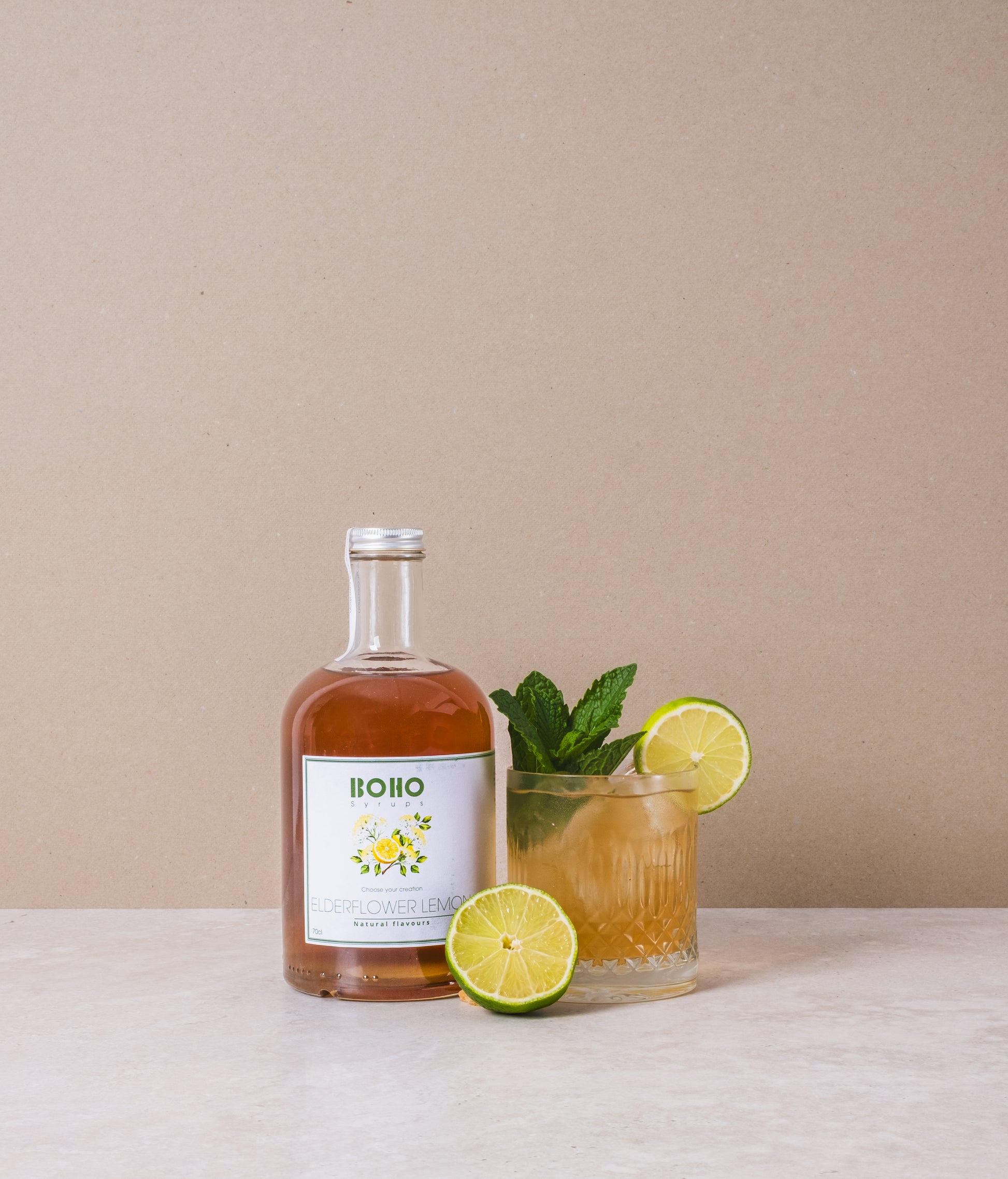 Fles BOHO vlierbloesem citroen siroop met daarnaast een mooi gegarneerde limonade – bloemig en verfrissend drankje